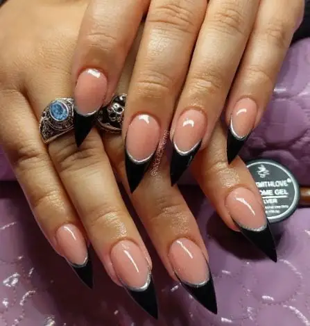 Clean nude stiletto nails with black tips and silver lines