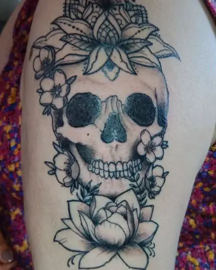 Skull Decorated With Lotus Flowers Tattoo Design