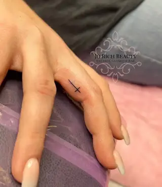 small cross tattoo on finger