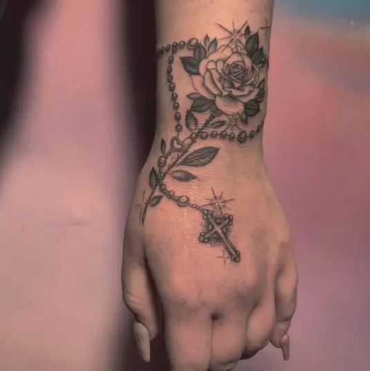 A rose and a rosary hand tattoo