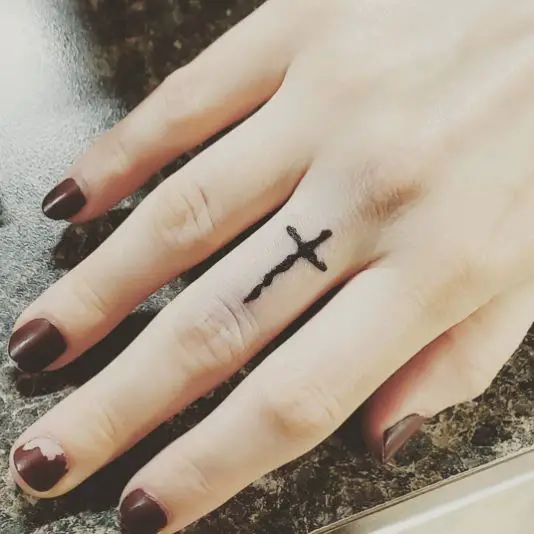 Black Cross Tattoo On Middle Finger