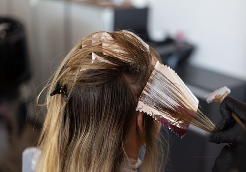 Colourist putting hair dye on a lock of hair with foil