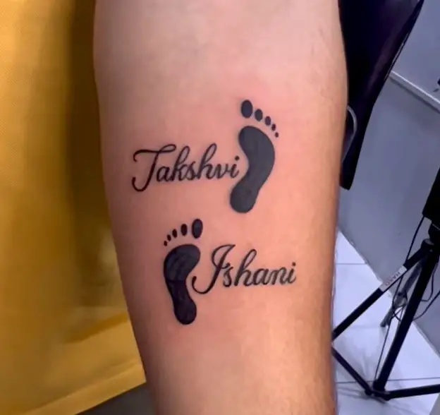 black tattoo with two footprints and two names