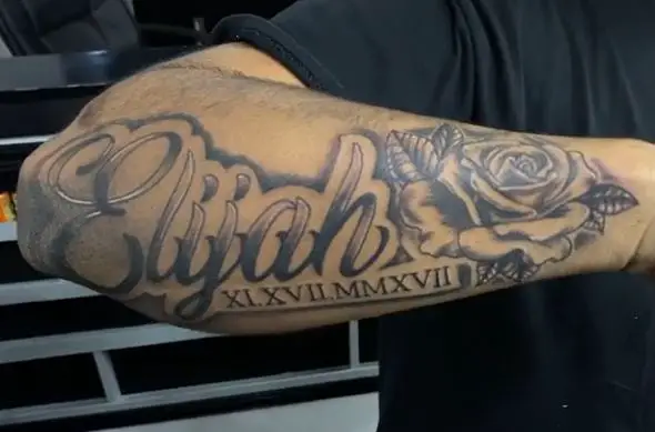 large name tattoo with date and flowers