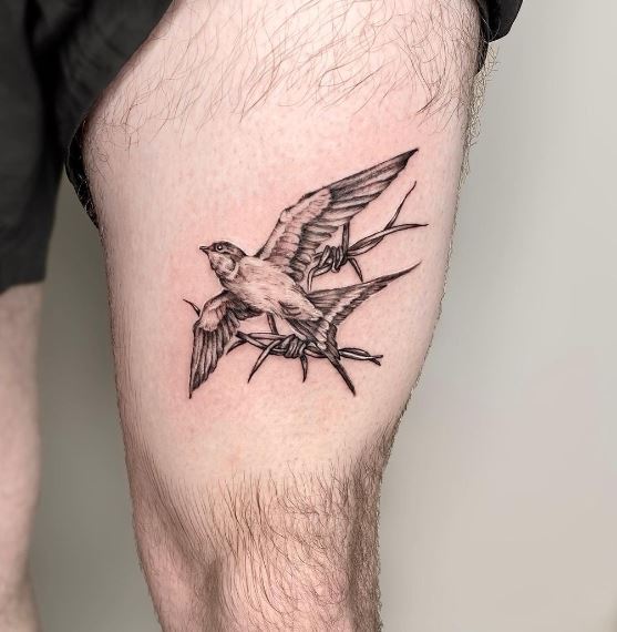 Black and White Swallow Thigh Tattoo with Barbed Wire Background