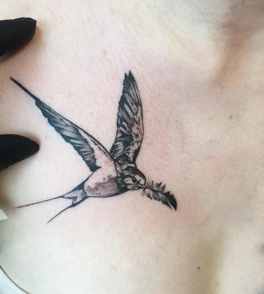 Black Flying Swallow with Feather in Beak Tattoo