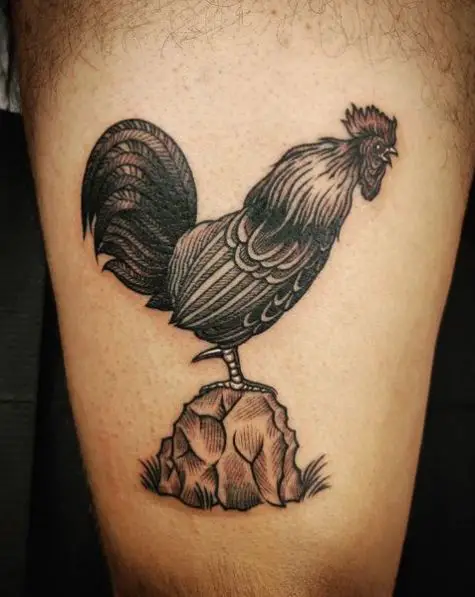 Tattoo of a Black and Grey Rooster Standing on a Stone