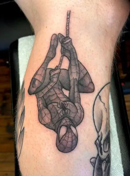 Grey Shaded Hanging Upside Down Spiderman Leg Tattoo