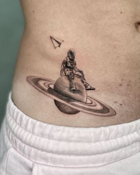 Astronaut on Saturn with Paper Rocket Hip Tattoo