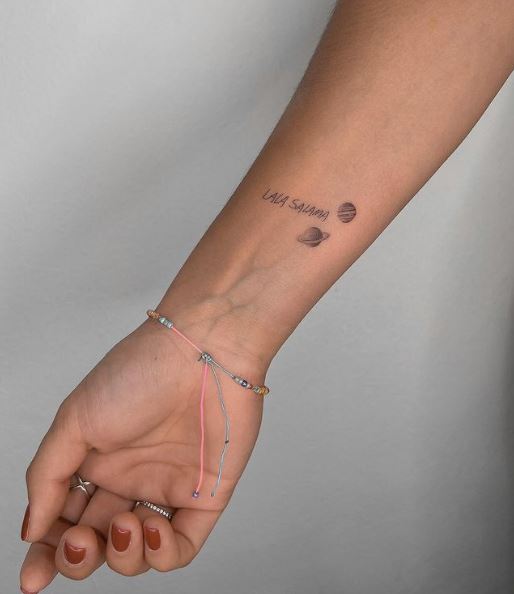 Tiny Saturn and Jupiter Lettering Wrist Tattoo