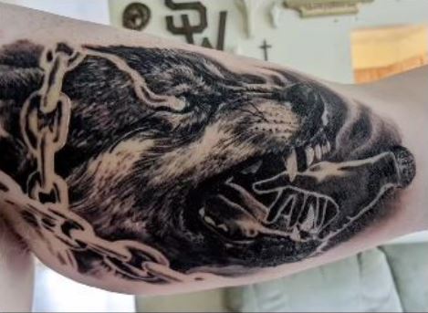 Human Hand and Wolf in Chains Inner Biceps Tattoo