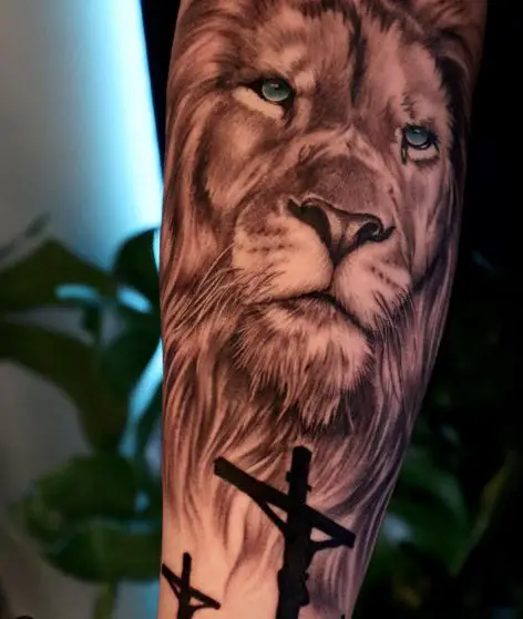 Crucifixion and Lion with Blue Eyes Forearm Tattoo