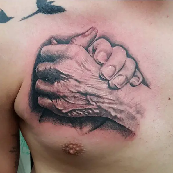 Hand Holding Aged Hand Chest Tattoo