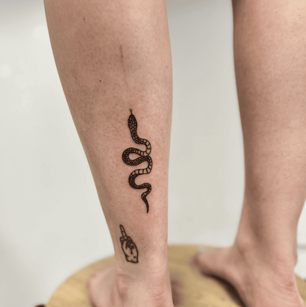 Black Snake Below The Middle Finger Tattoo