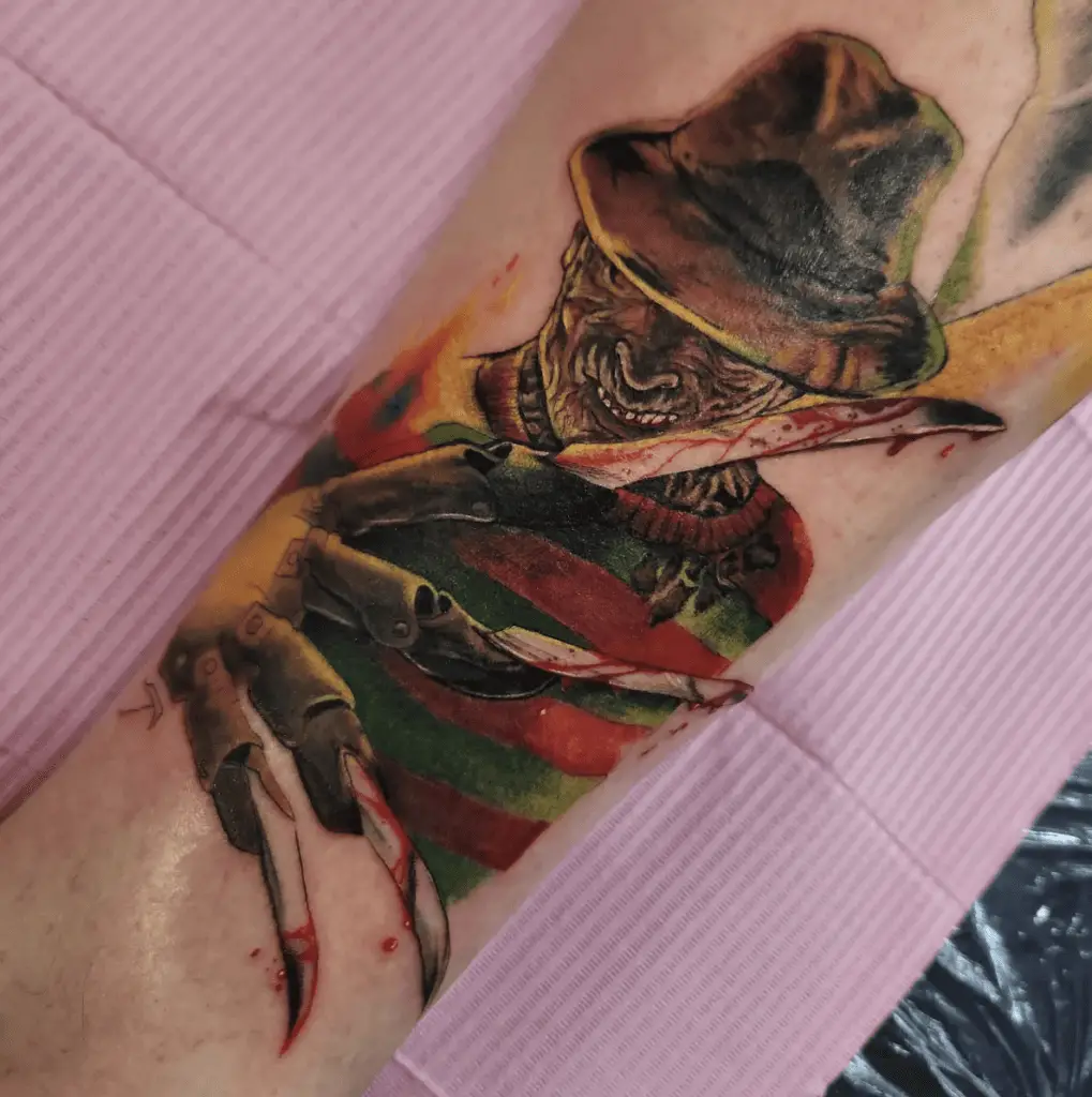 Colored Man Laughing With Bloody Claw Gloves Arm Tattoo