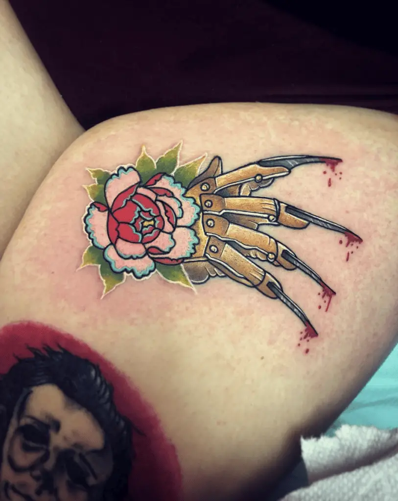 Colored Mechanical Hand With Sharp Razor Nails and Flower Thigh Tattoo