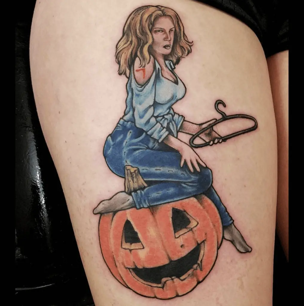 Colored Messed Lady Holding A Hanger And Sitting On A Halloween Pumpkin Thigh Tattoo