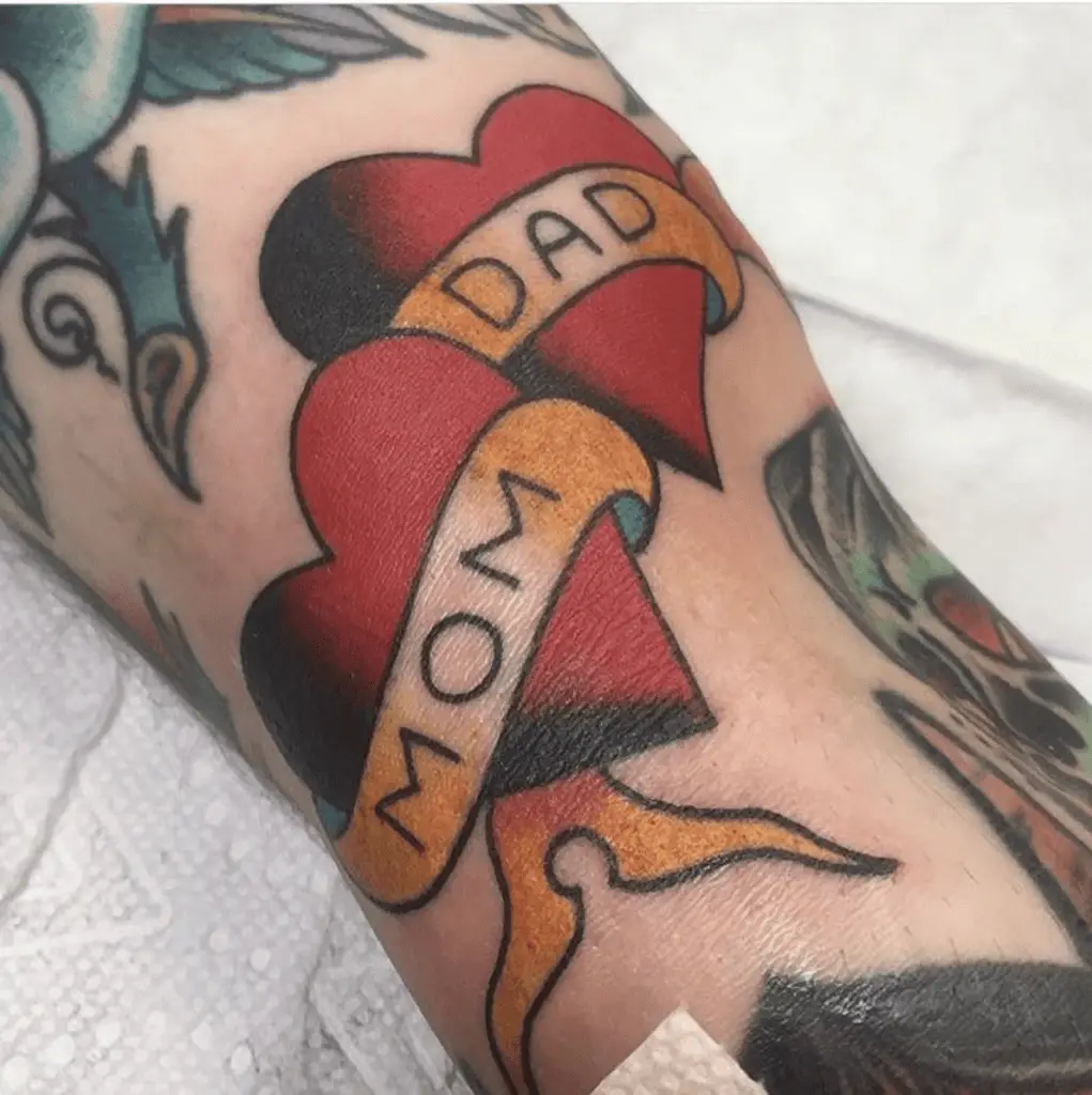 Colored Mom and Dad in Two Classic Heart With Ribbon Arm Tattoo