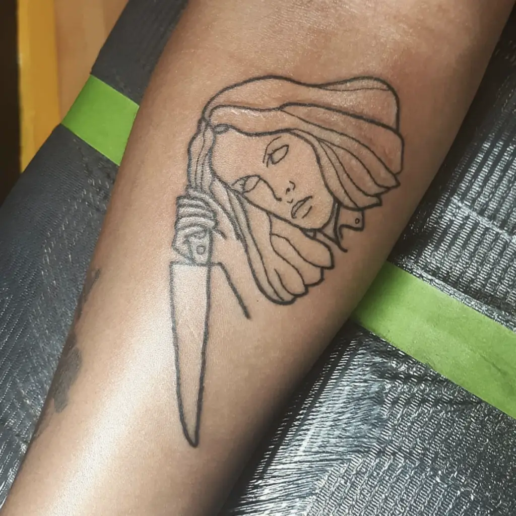 Outline of a Woman Holding a Knife Arm Tattoo