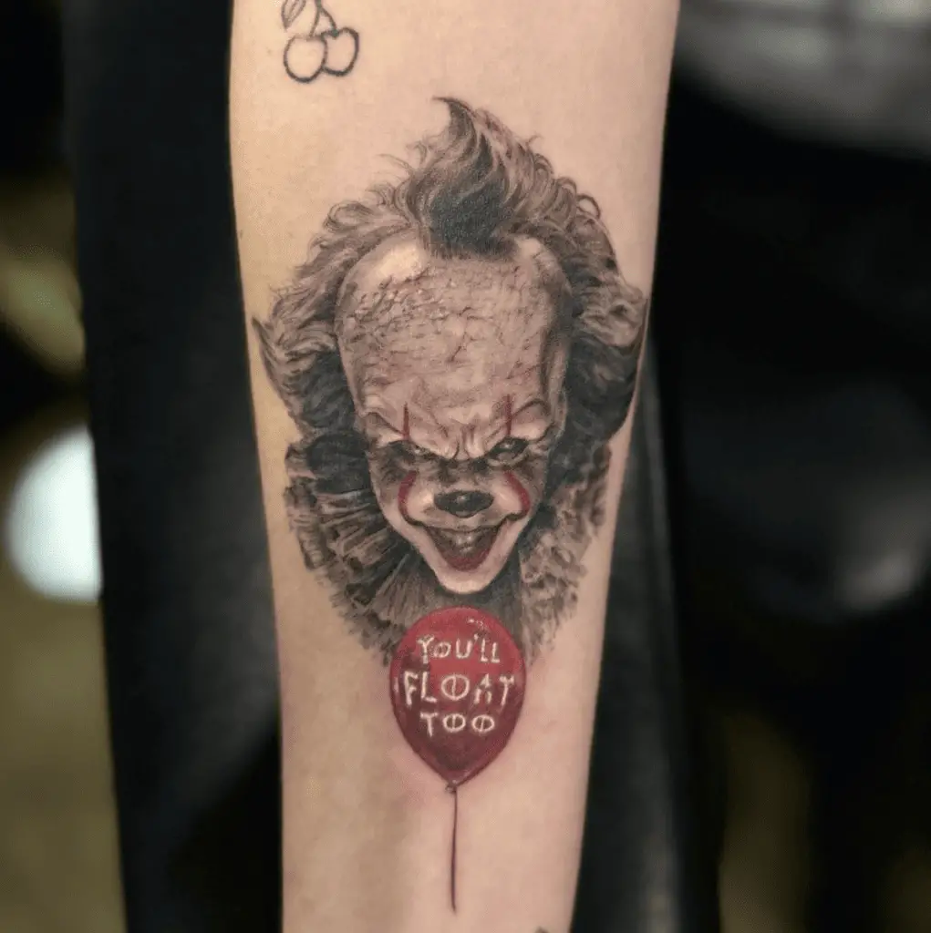 Scary Clown With A You All Float Too Written Red Balloon At The Bottom Arm Tattoo
