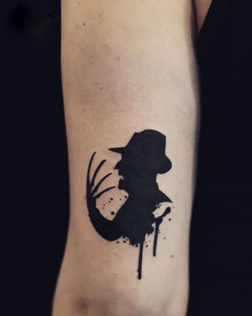 Solid Black Side View Man Wearing a Hat and has Razor-Sharp Fingers Arm Tattoo