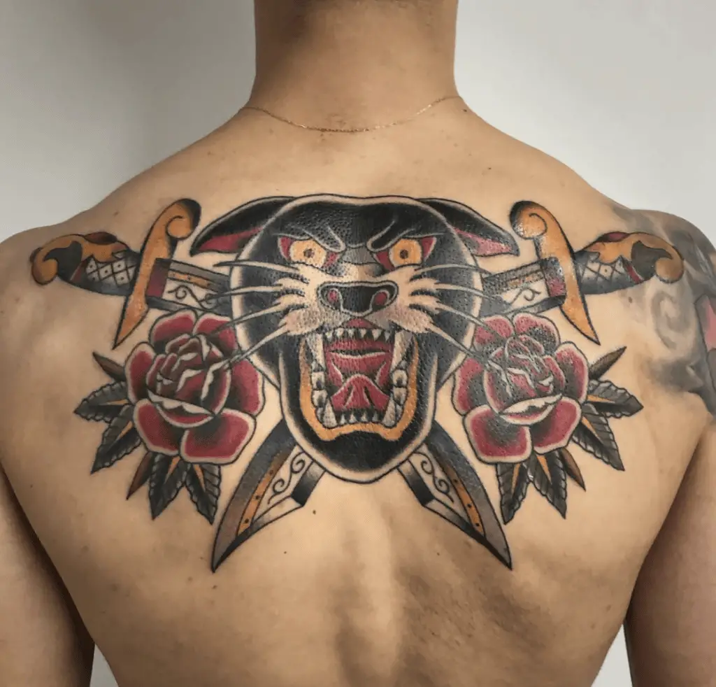 Colored Black Roaring Panther With Crossed Dagger and Two Two Roses Background Back Tattoo