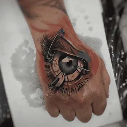 Colored Eye With Safety Pin and Needle Hand Tattoo
