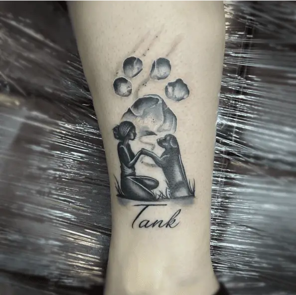 A Girl Holding her Dog Paw in a Grass Field with Pet Paw Print Background Ankle Tattoo